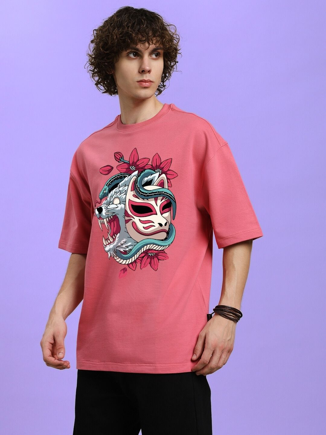 Model wearing KITSUNE WOLF PRINTED OVERSIZED T-SHIRT PINK, featuring a bold wolf motif on blush-pink fabric, for a stylish streetwear look.