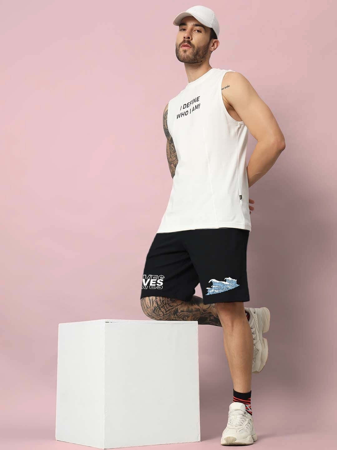 Man wearing 3D WAVES REGULAR FIT SHORTS BLACK and white t-shirt with pink background.
