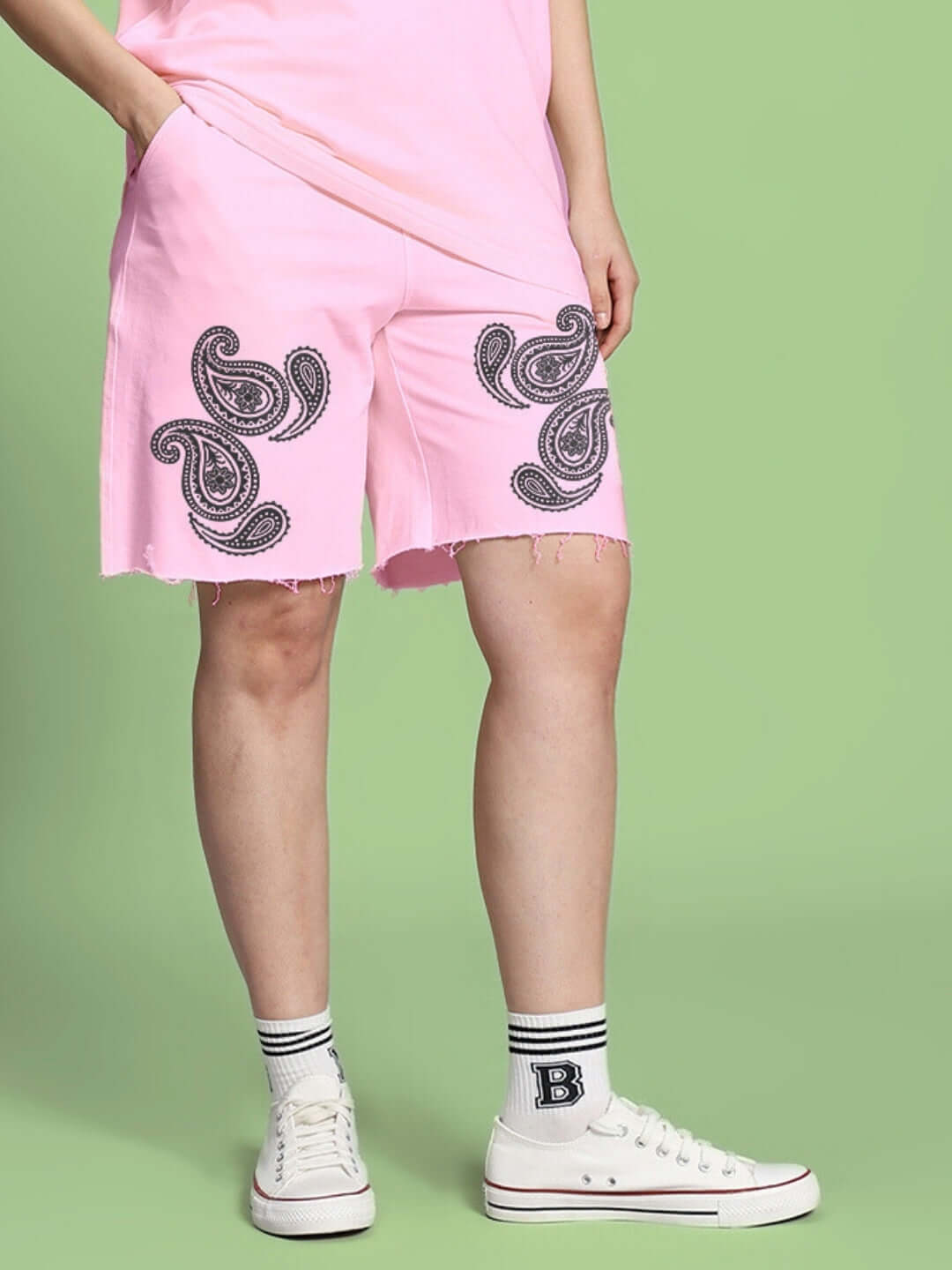 Pink women's shorts with paisley print, regular fit, shown with casual outfit on green background.
