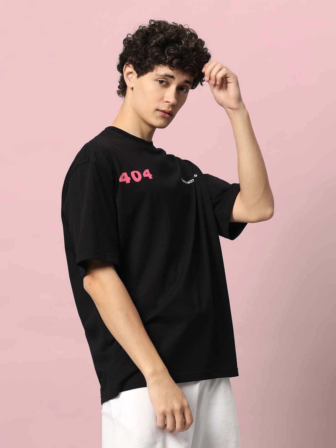 Model wearing 404 ERROR OVER-SIZED T-SHIRT BLACK with pink text on pink background