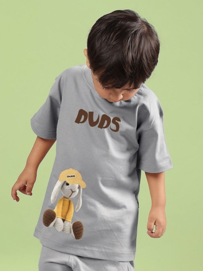 Child wearing grey Flint Bunny t-shirt with bunny graphic, suitable for boys and girls, on a green background.