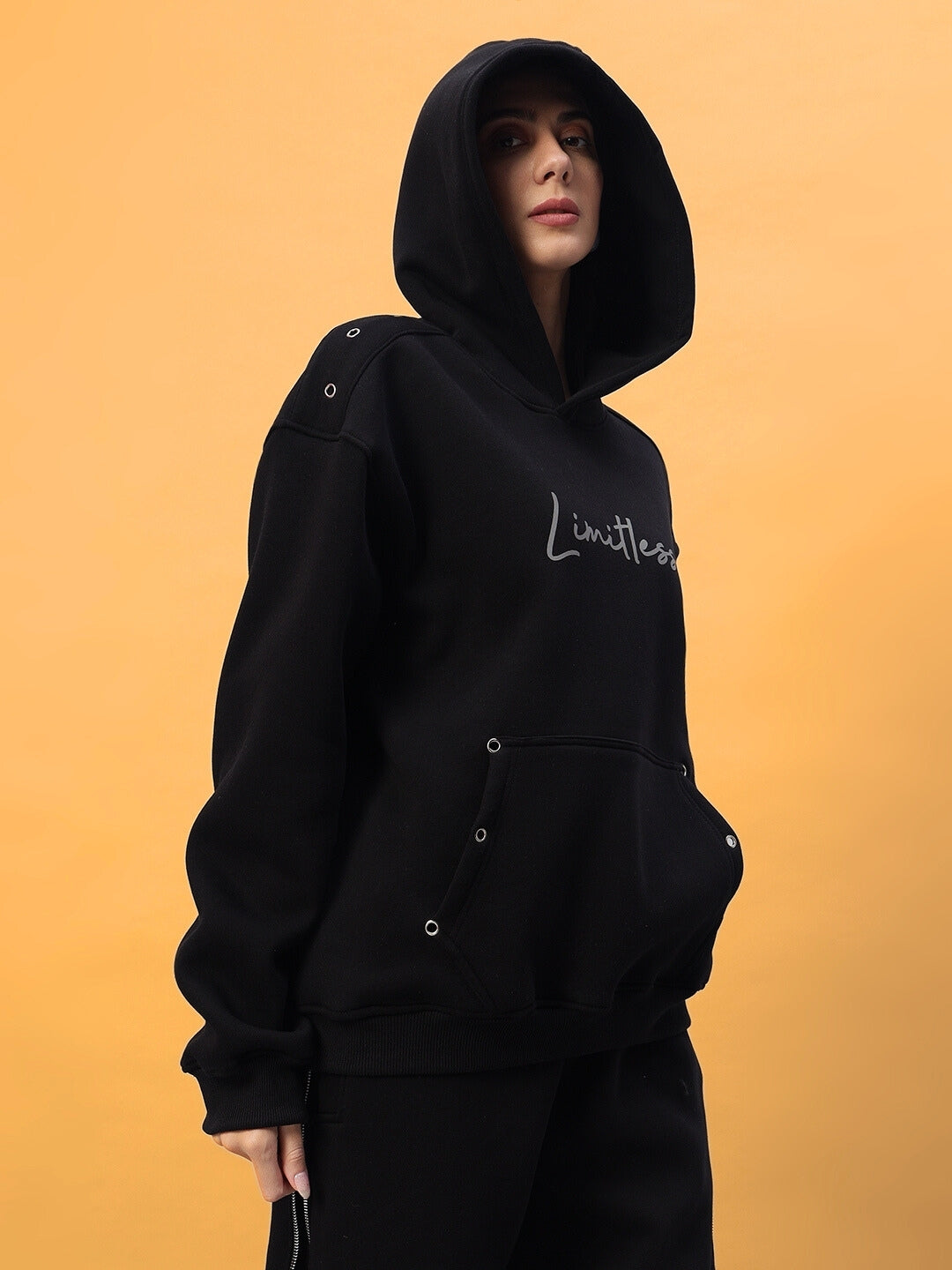 Black Women's Limitless Fleece Reflector Co-Ord with hood, featuring stylish design against a yellow backdrop.