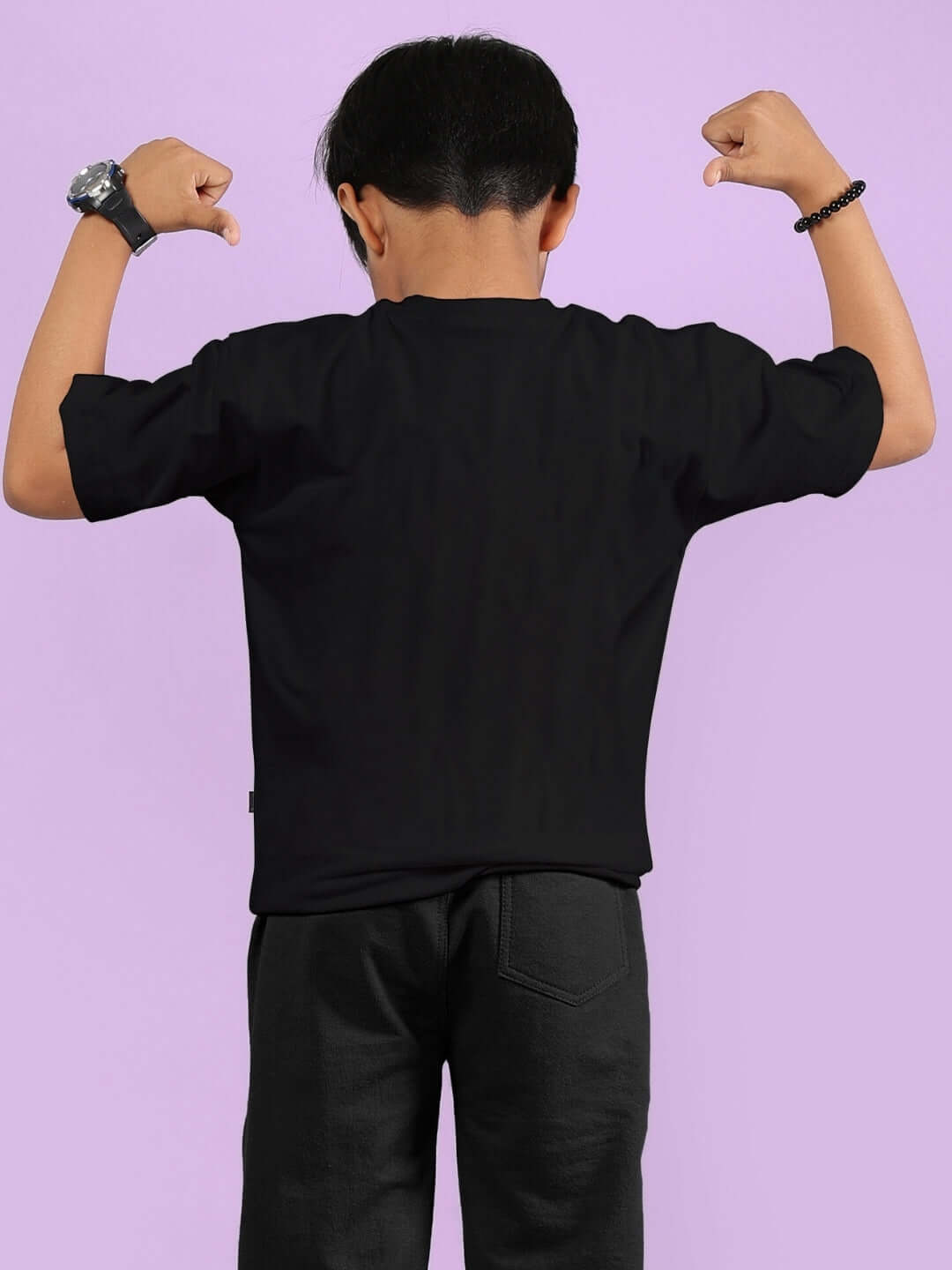 Child flexing in black hip hop teddy t-shirt for boys & girls, showcasing stylish design on a purple background.