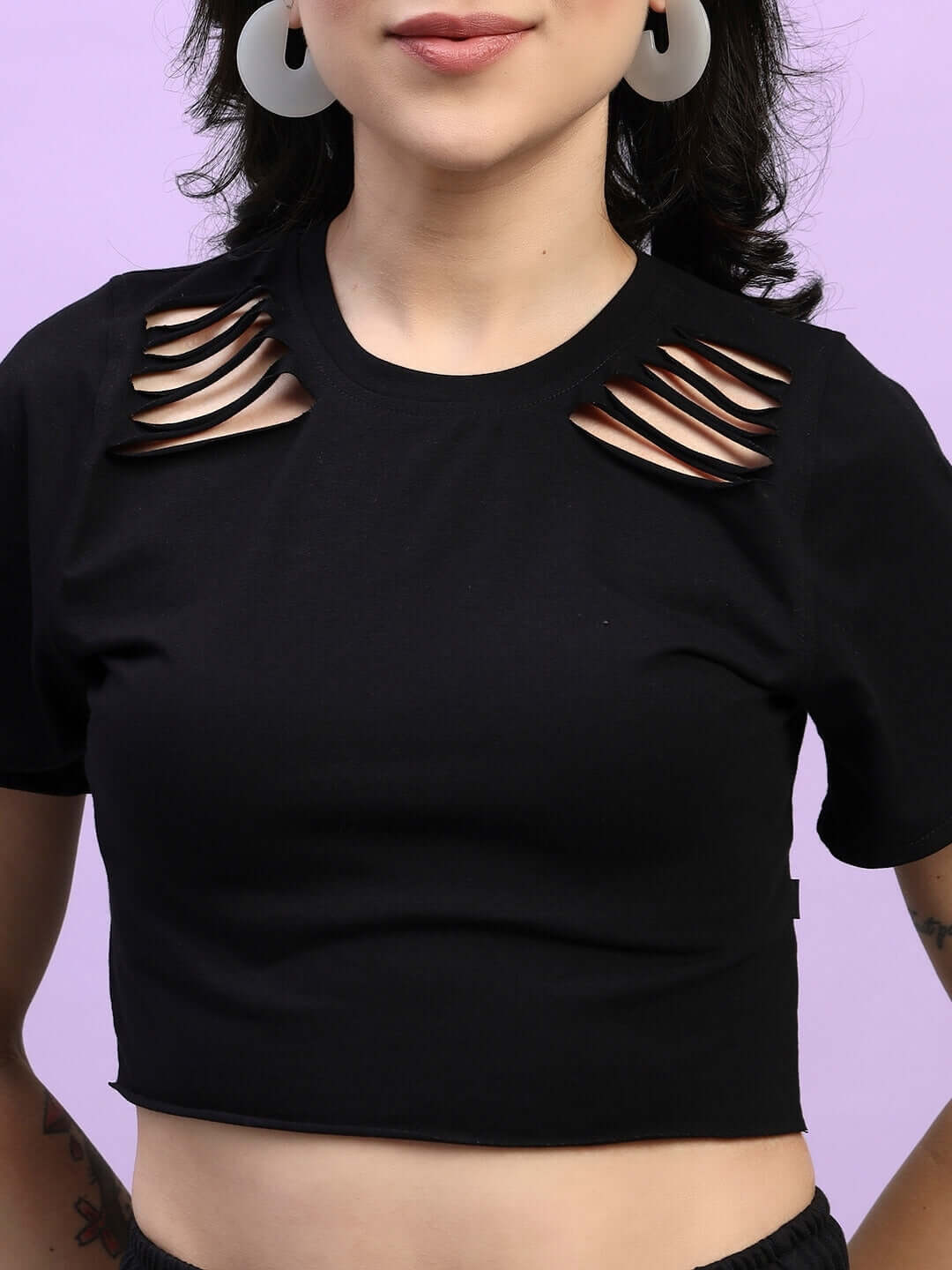 Black women's top with cut-out shoulder design, featuring modern styling against a pastel purple background.