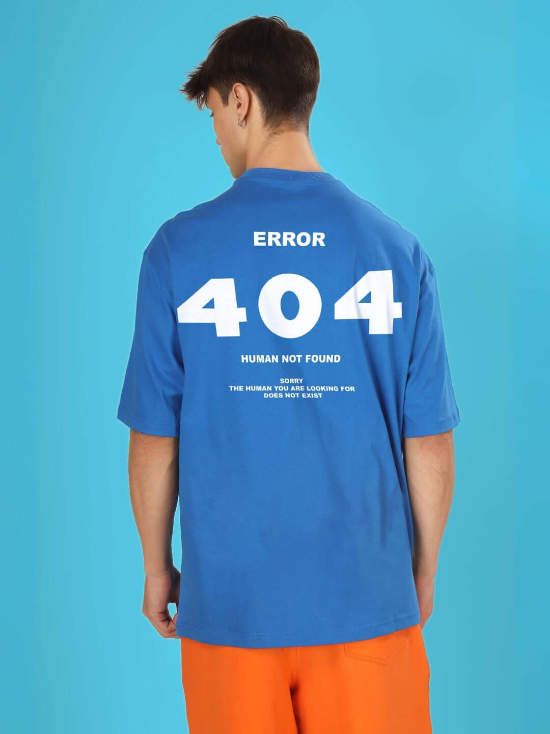 404 ERROR OVER-SIZED T-SHIRT ROYAL BLUE with tech-themed design, modeled by person wearing orange shorts on blue background.