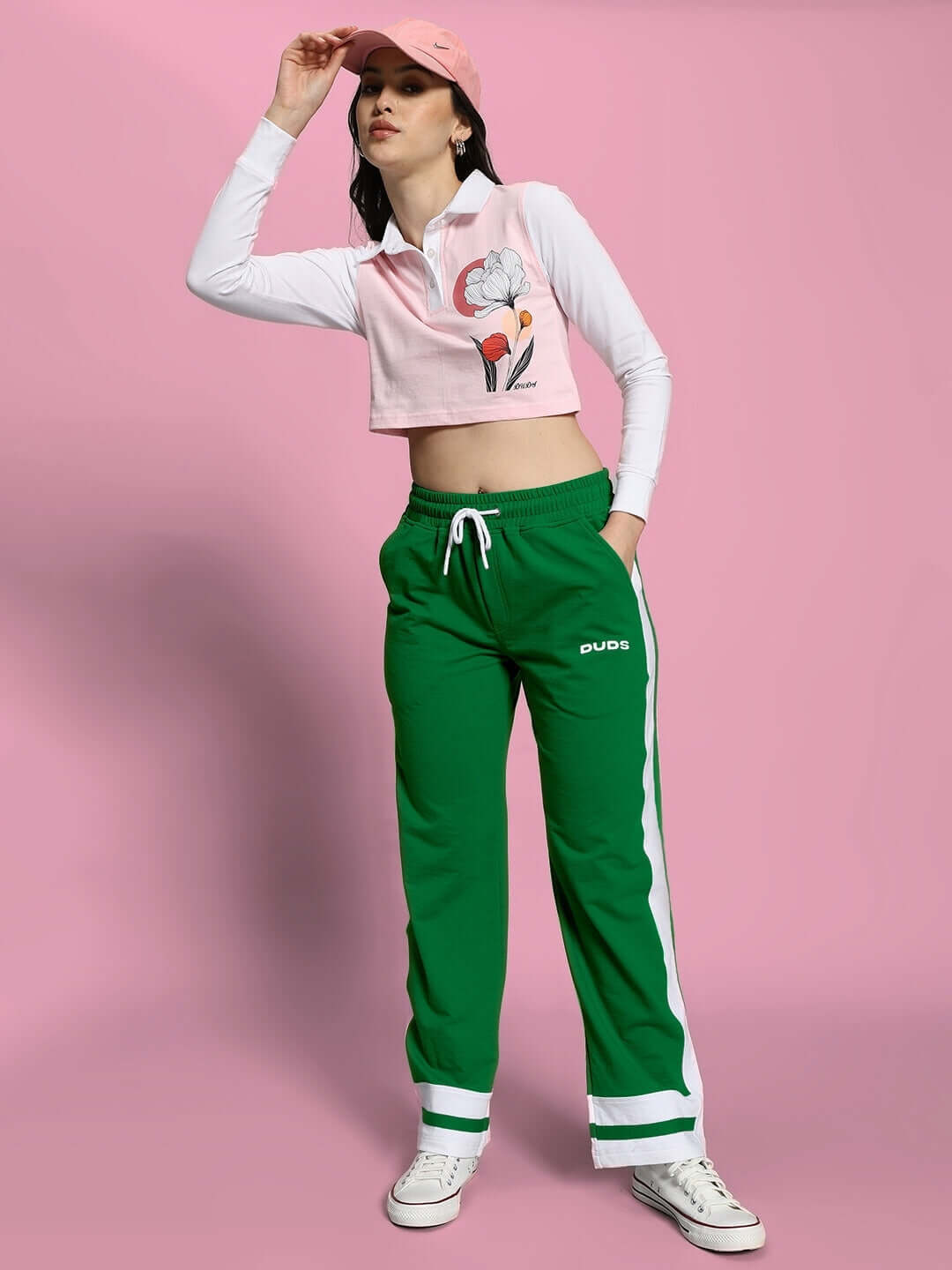 Model wearing Women's Ronny Side Stripe Jogger in green with white stripe, styled with a pink top and cap, by DUDS.