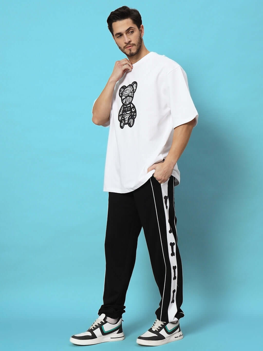 Model wearing TIBIA CONTRAST PANEL JOGGERS BLACK with white tee and sneakers against a blue background.