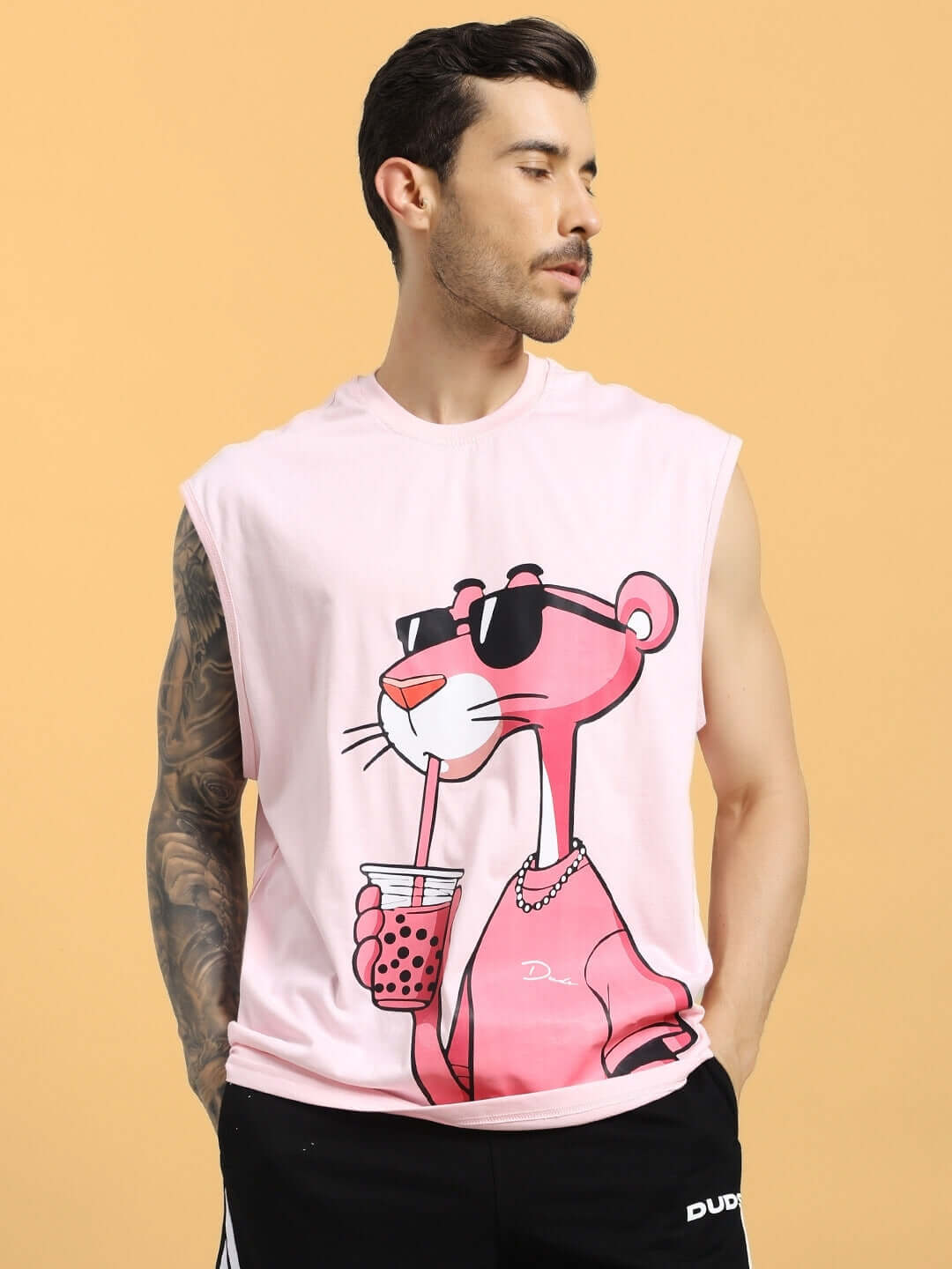 Man wearing a pink t-shirt featuring a Pink Panther design, holding a drink with sunglasses; ideal for custom fit orders.
