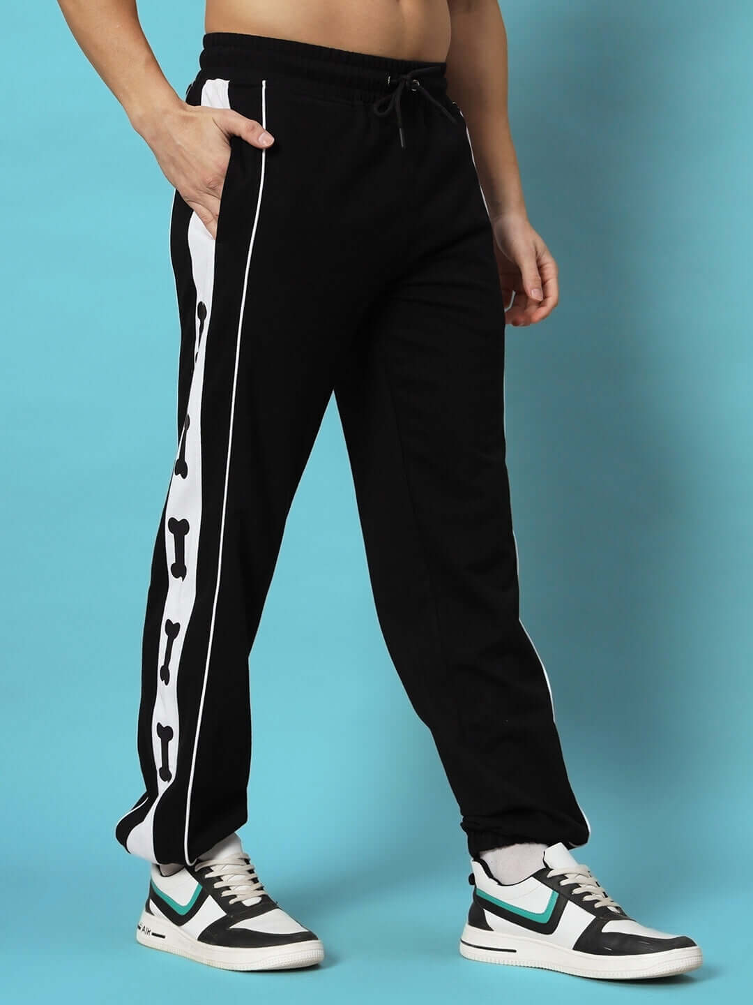Person wearing TIBIA CONTRAST PANEL JOGGERS BLACK with unique side design on a blue background