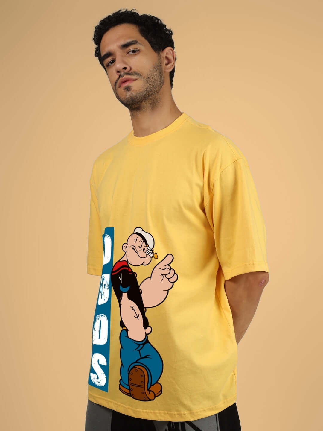 Person wearing POPEYE OVER-SIZED T-SHIRT YELLOW with cartoon character design on the front.