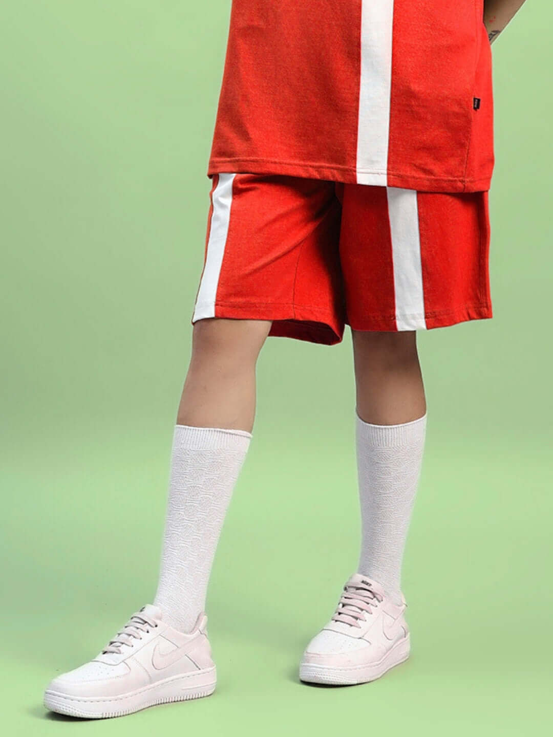 Women's red wideline regular fit shorts with white stripe, stylish and customizable for a perfect fit, paired with white socks and sneakers.