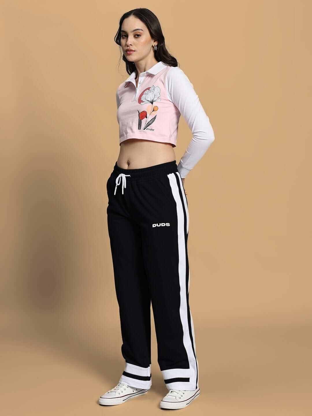 Model wearing Women's Flora Co-Ord Set in pink and black, featuring a floral top and black drawstring pants. Stylish and comfortable fashion.