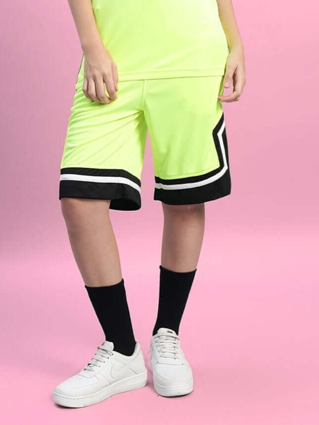 Model wearing Women's Armado Regular Fit Neon Green Shorts with black and white trim, paired with white sneakers and black socks.