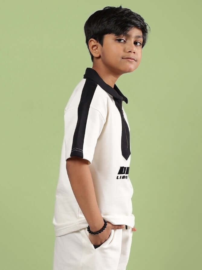 Young boy wearing off-white Splinter T-shirt by DUDS, featuring black stripes and casual fit, suitable for boys and girls.
