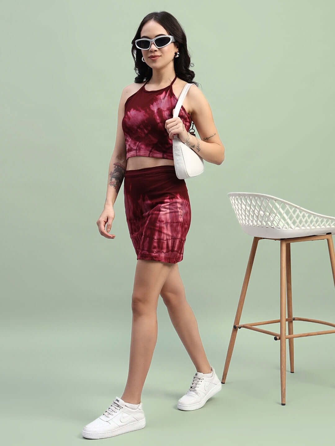 Woman wearing maroon tie-dye co-ord set with sneakers and a white bag, showcasing an outfit made of premium cotton French Terry Lycra.