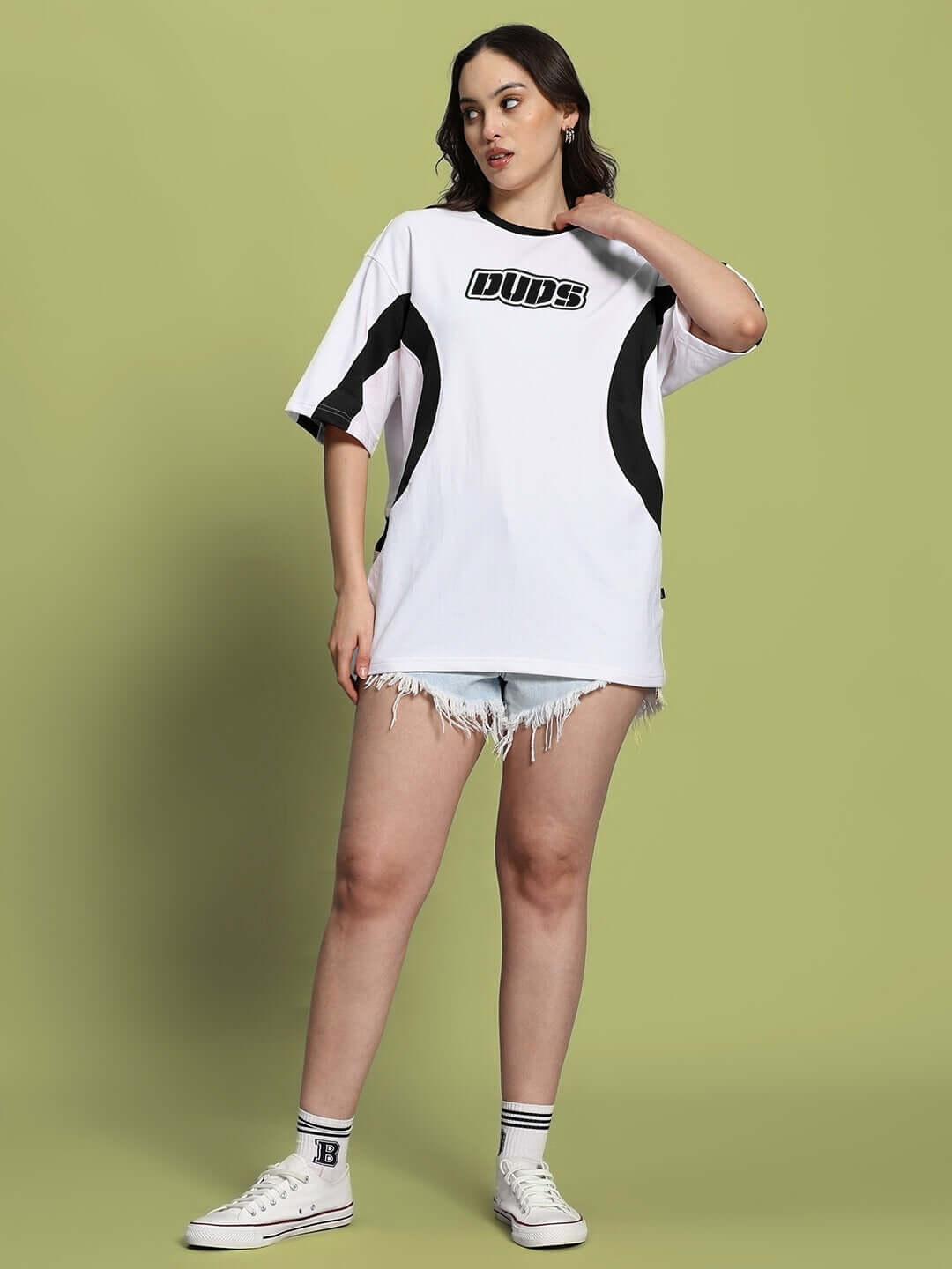 Women's oversized white and black EZEL t-shirt styled with denim shorts and sneakers, perfect for casual wear.
