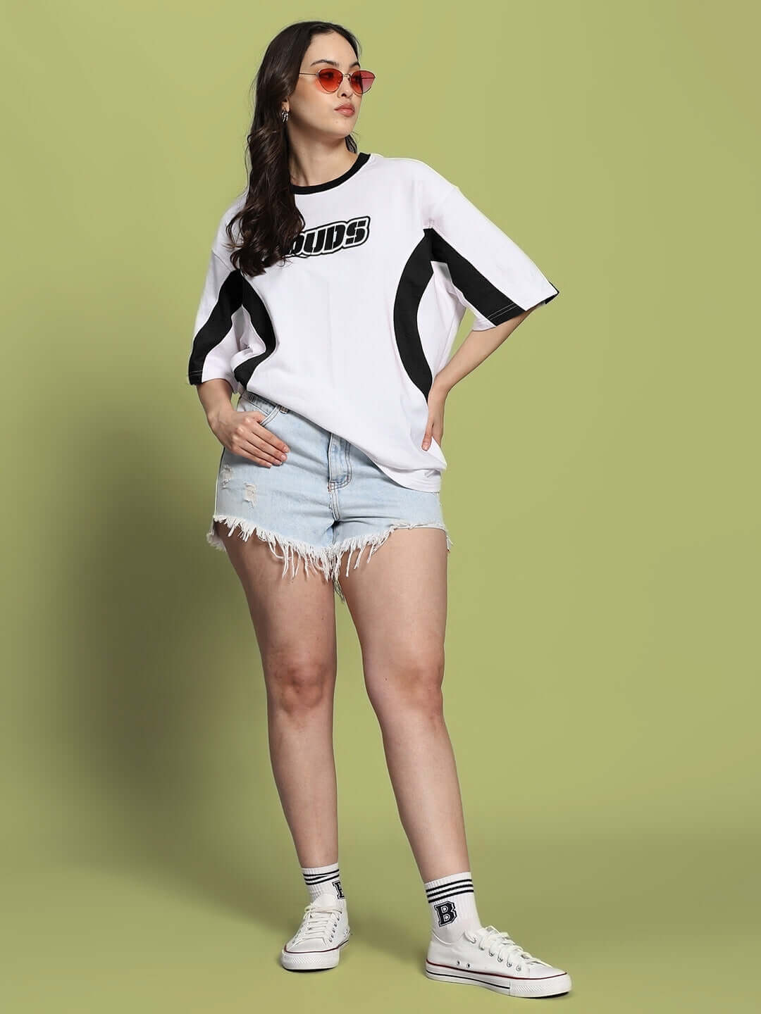 Model wearing WOMEN'S EZEL oversized T-shirt in white-black, paired with denim shorts, showcasing casual style, front view.