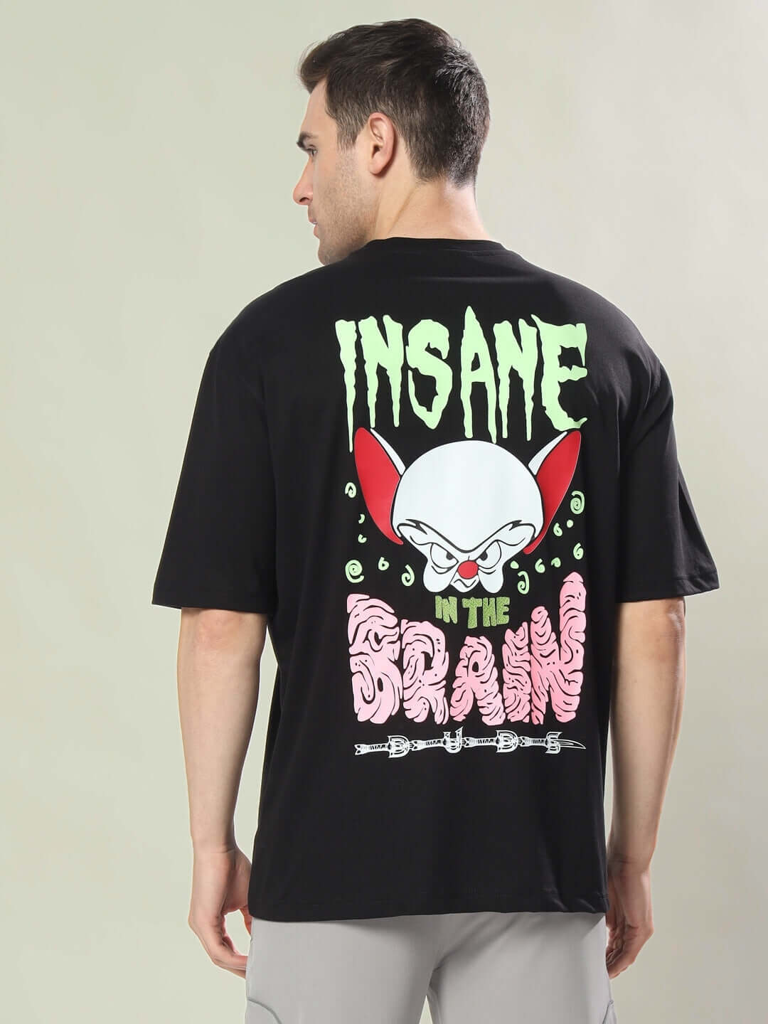 Man wearing INSANE BRAIN OVER-SIZED T-SHIRT BLACK with graphic design on the back showcasing a cartoon brain and text.