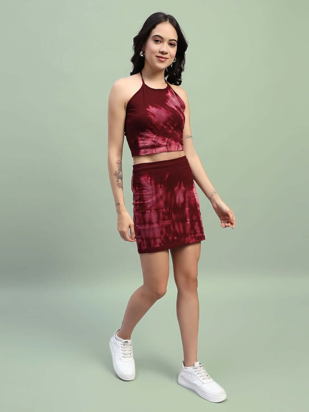 Model wearing maroon tie-dye co-ord set, featuring a crop top and skirt with white sneakers, made from premium cotton French terry lycra.