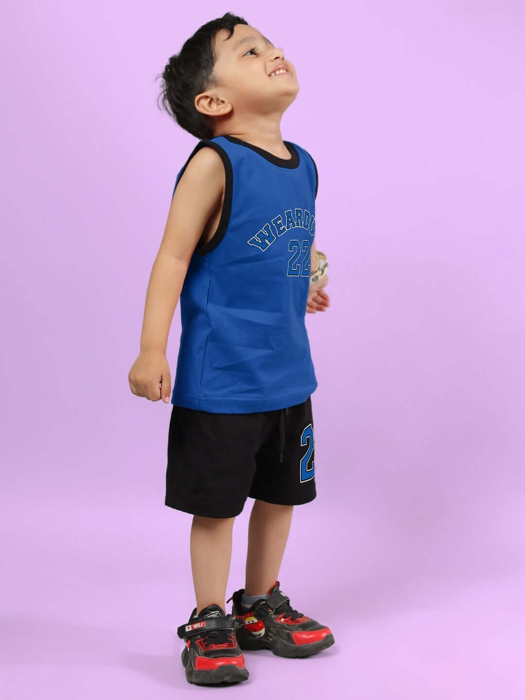 Child wearing blue and black AMIGA co-ord outfit by DUDS, featuring a blue tank top and black shorts with red-accented sneakers.