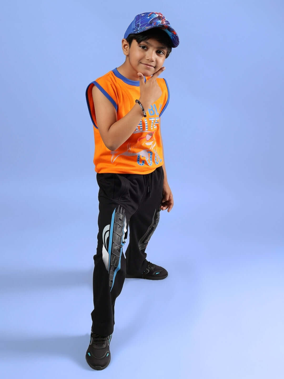 Child wearing orange Buffy t-shirt for boys and girls from DUDS, standing confidently in casual attire against a blue background.