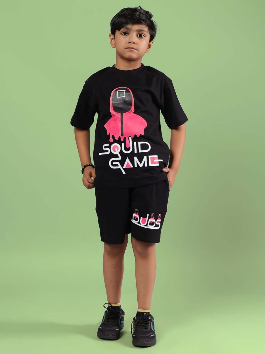 Child wearing black Squid Games co-ord set featuring graphic tee and shorts from DUDS brand.