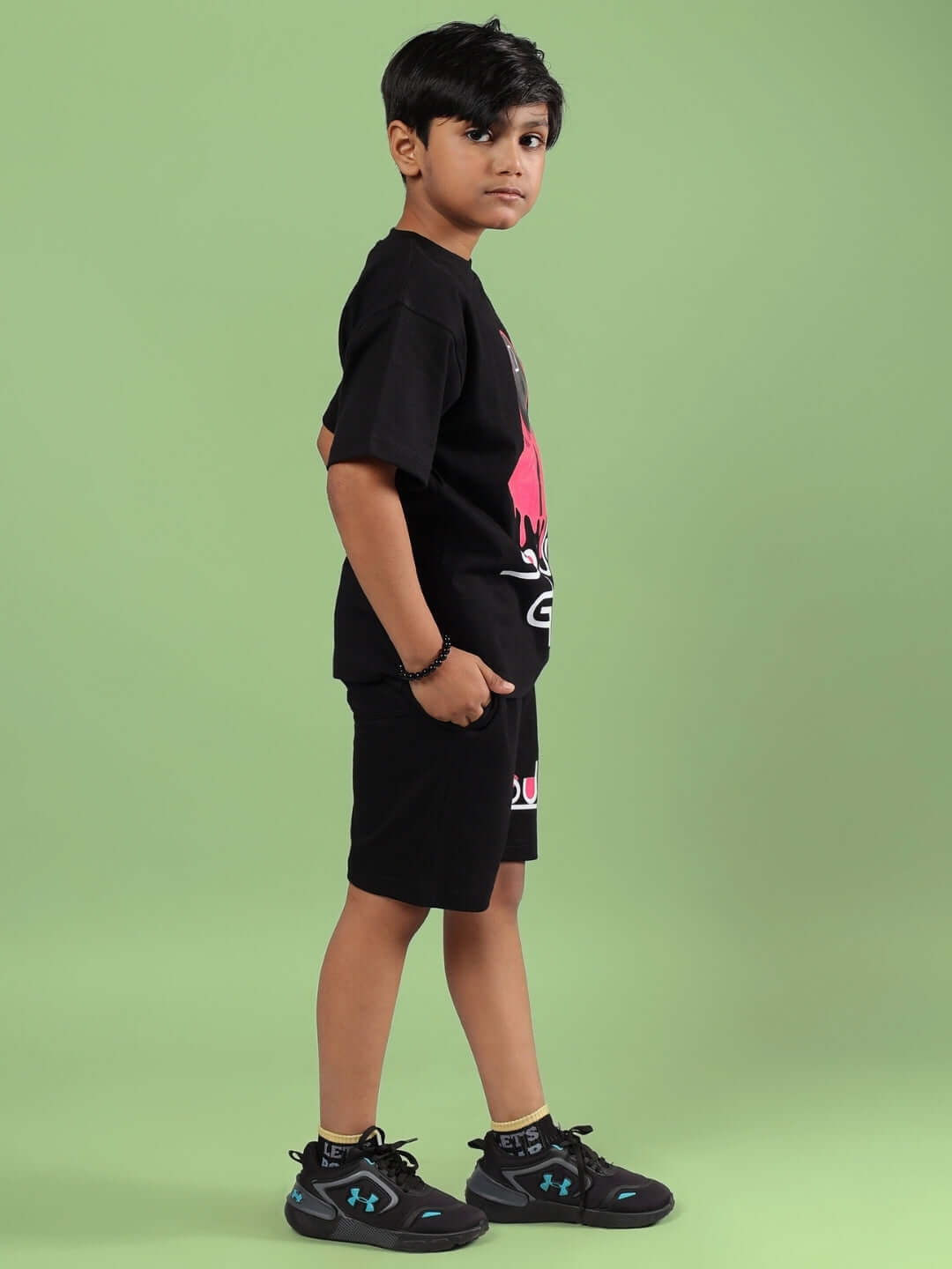 Child wearing black Squid Games co-ord set by DUDS against a green background
