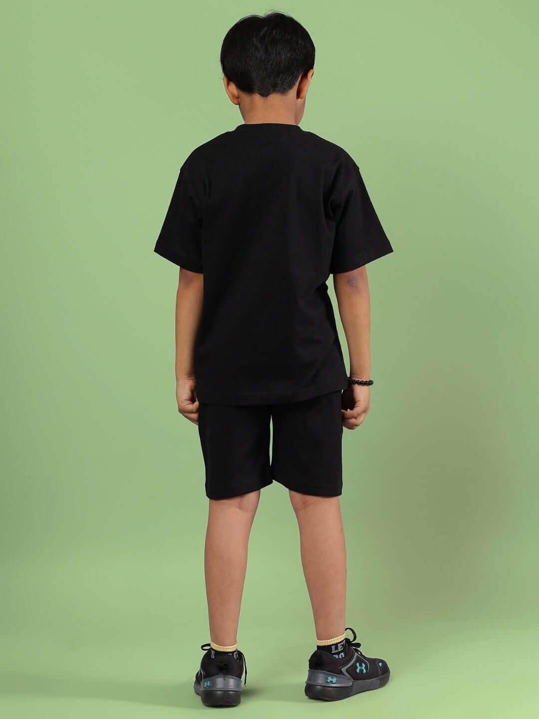 Back view of child wearing black Squid Games co-ord set for boys and girls against a green background.