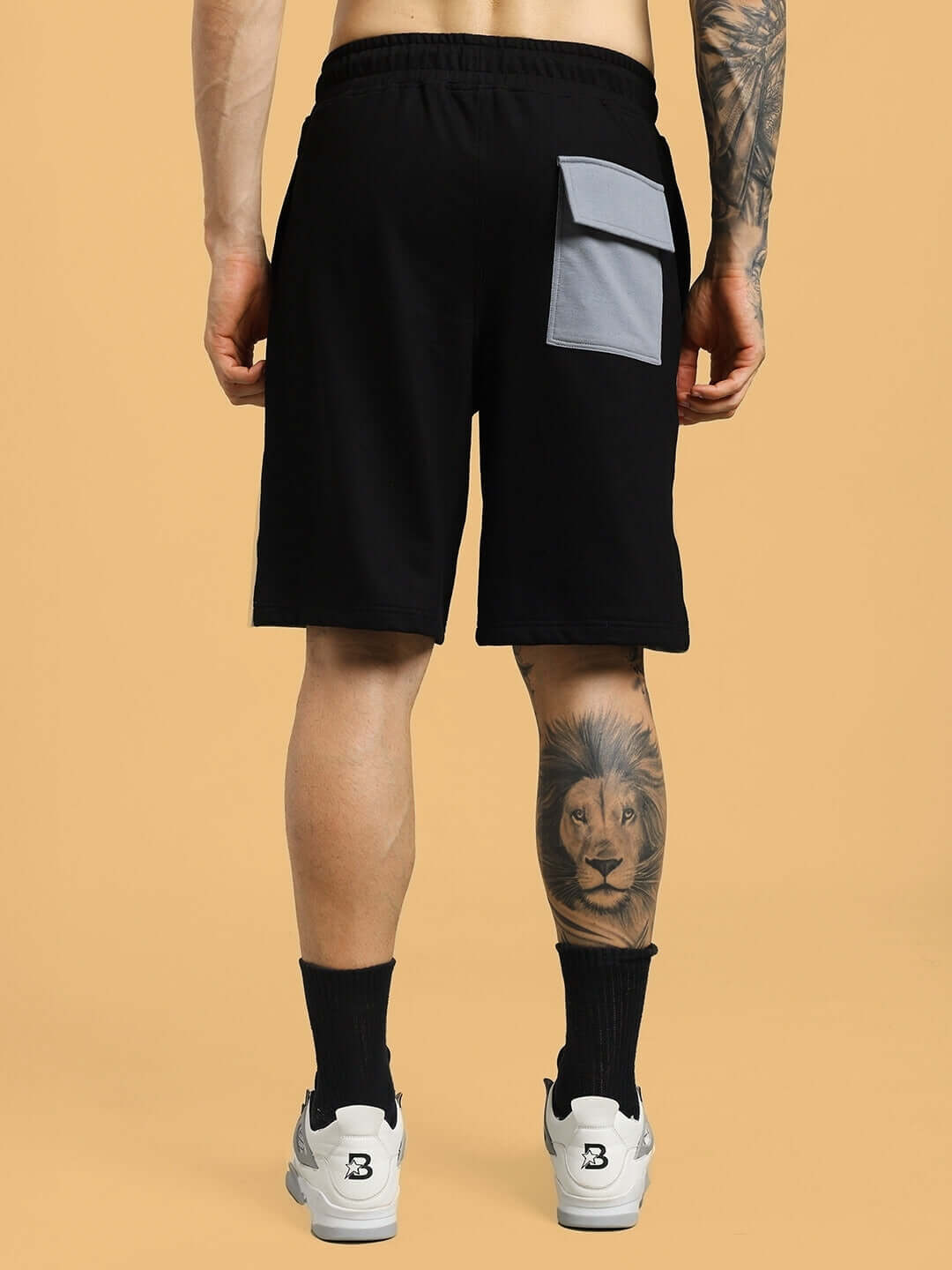Back view of black-grey Lewin Chino regular fit shorts with custom fit option, shown on a person with a lion tattoo on the calf.