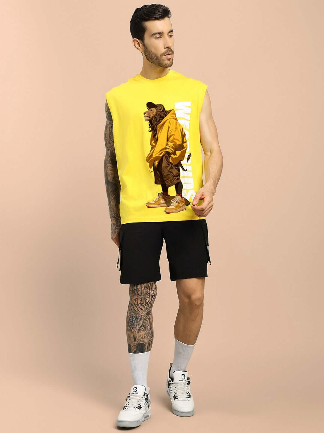 Man wearing yellow Street Lion Gym T-shirt featuring design, paired with black shorts and white sneakers, standing against a beige background.