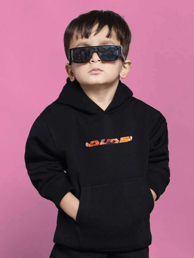 Child wearing black GOHAN co-ord set with sunglasses, pink background