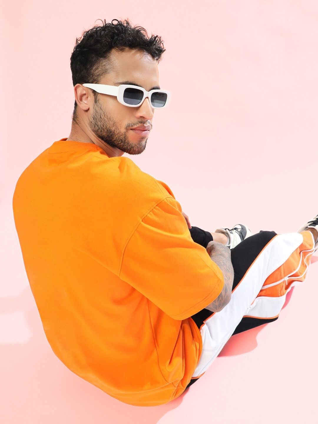 TOM AND JERRY TOAST OVERSIZED T-SHIRT ORANGE worn by male model sitting on pink background, wearing sunglasses
