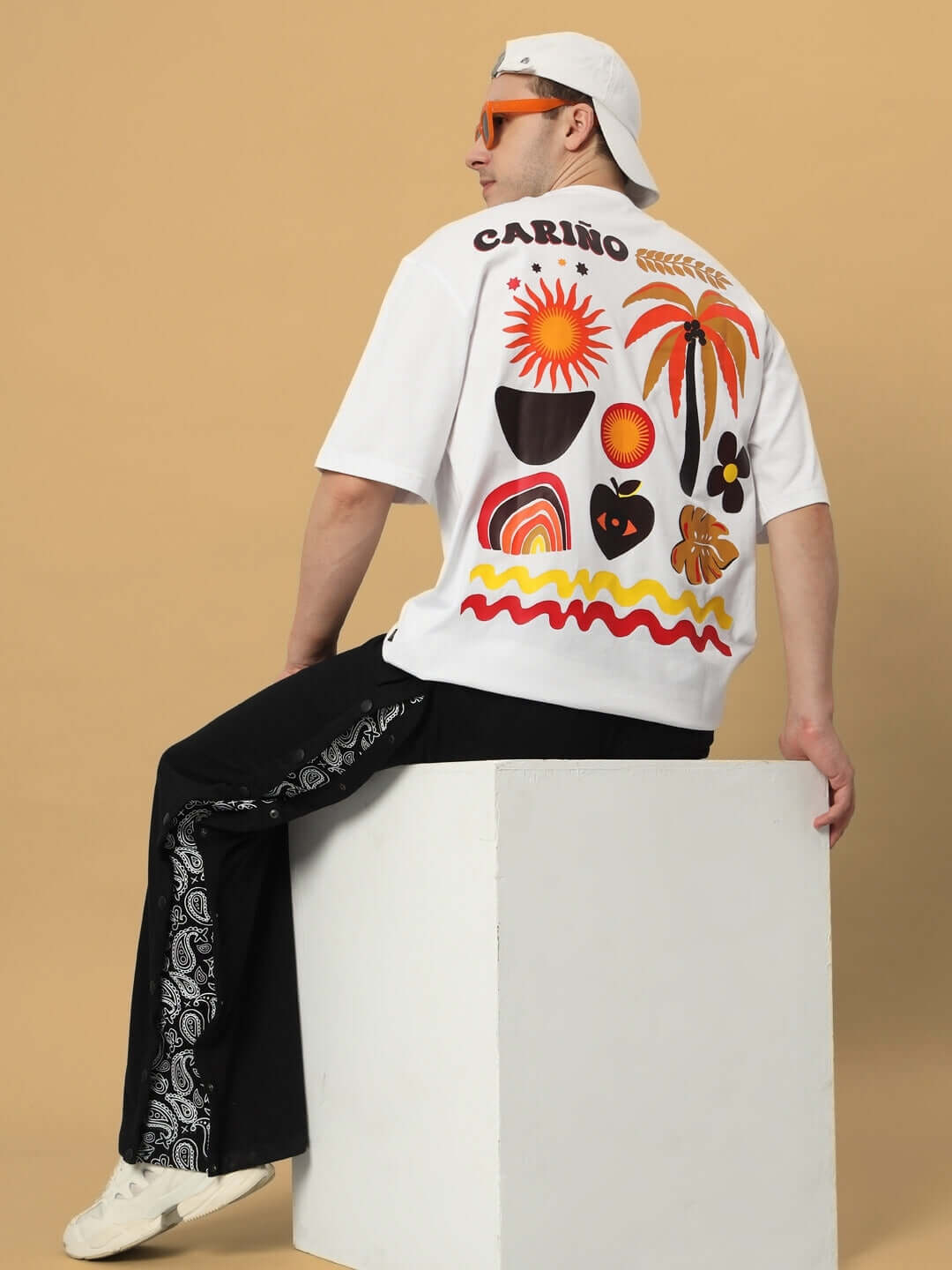 Back view of a model wearing a CARINO OVER-SIZED T-SHIRT WHITE with vibrant artistic designs.