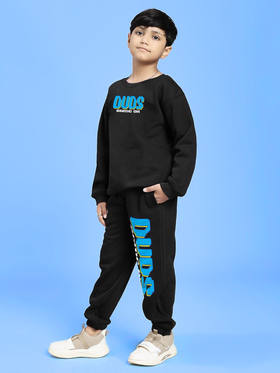 Child wearing GAME ON PRINT FLEECE CO-ORD FOR BOYS AND GIRLS BLACK with sporty graphics and sleek style against a blue background.