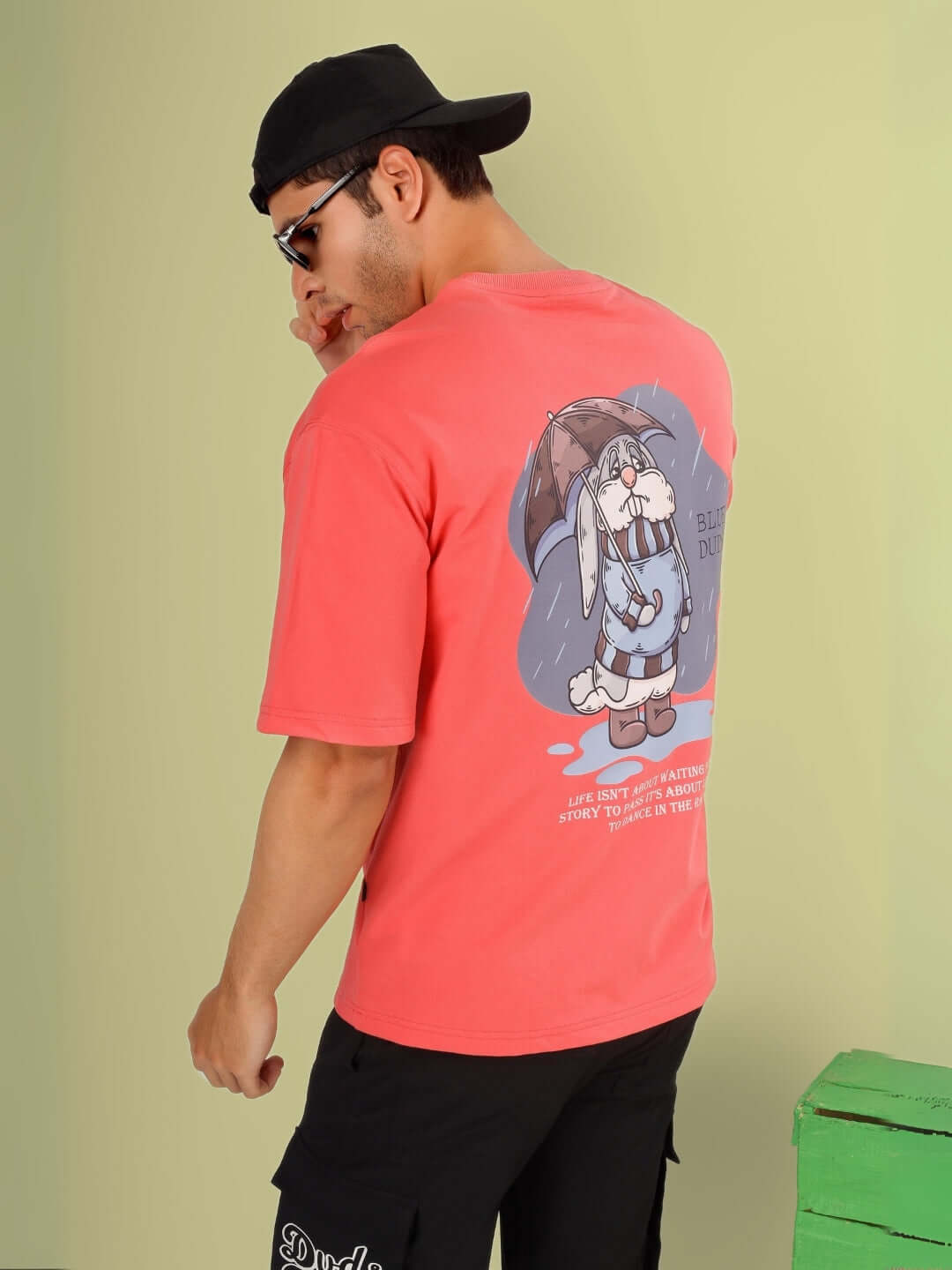 Man wearing BLUE LAPIN OVER-SIZED T-SHIRT PANTONE PEACH featuring cartoon graphic, premium heavy gauge fabric. Back view of clothing.