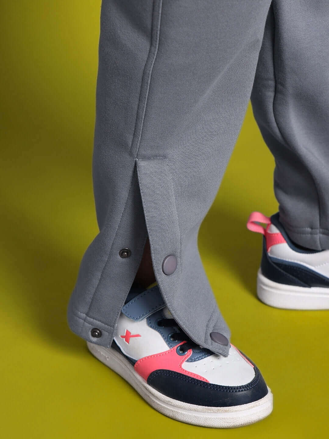 Close-up of a grey tabby fleece pant with button detail, worn with trendy sneakers, suitable for boys and girls.