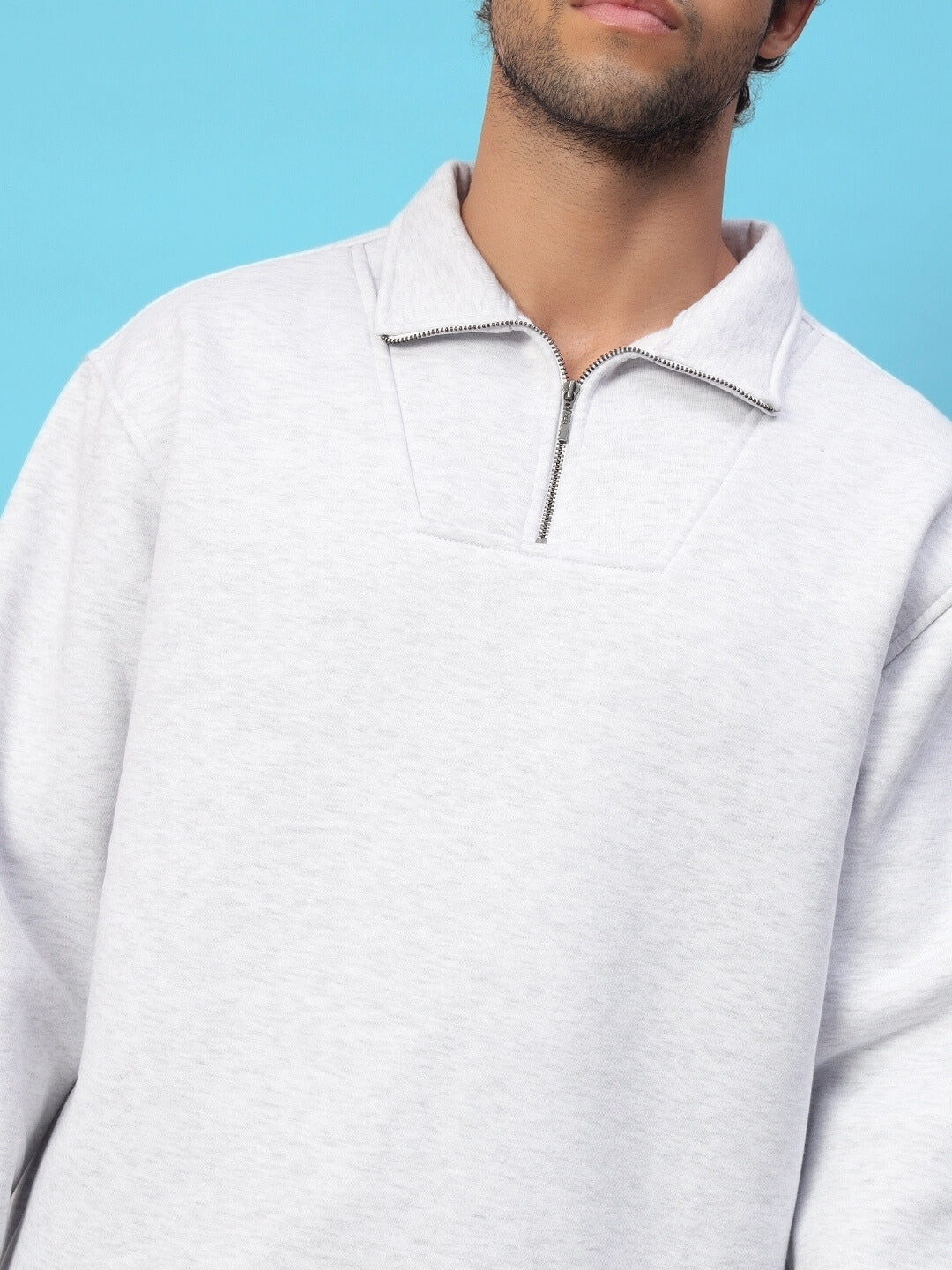 Close-up of person wearing Bona-Fide fleece co-ord in melange grey with half-zip collar against blue background.