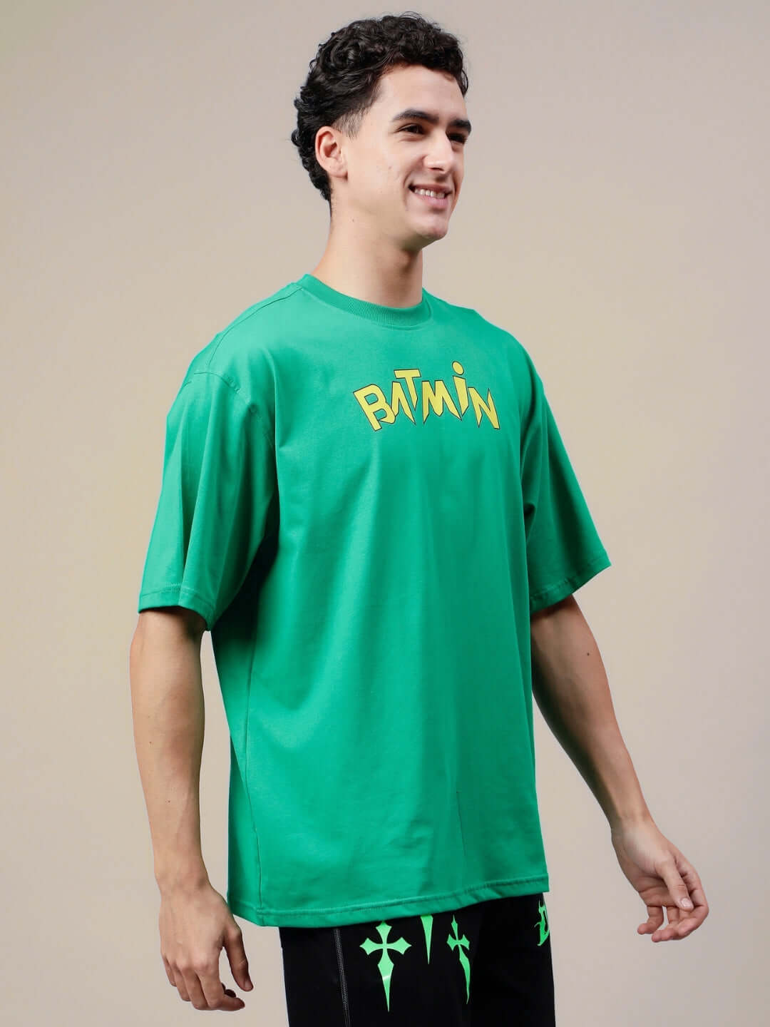 Model wearing BATMIN OVER-SIZED T-SHIRT GREEN, showcasing front view with bold logo design on a casual stylish oversized fit.