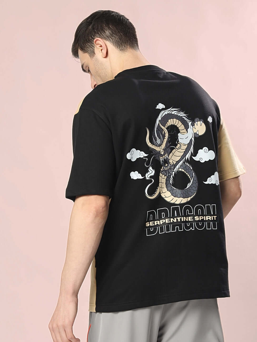 Man wearing DRAGON OVERSIZED T-SHIRT BLACK BEIGE with dragon graphic on back.