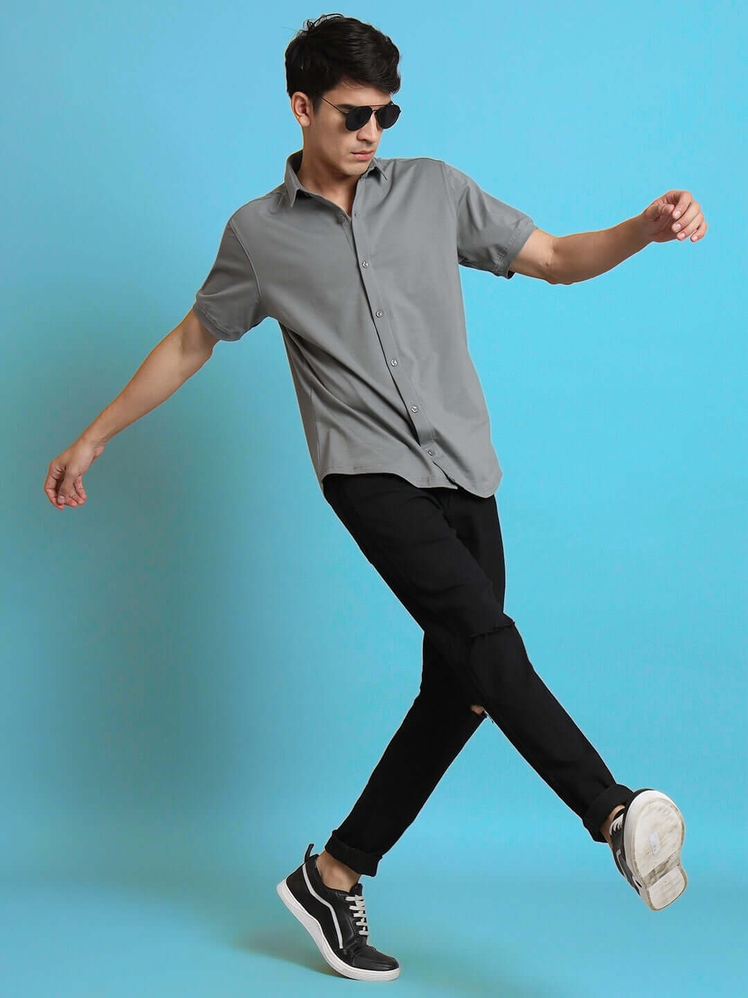 Man wearing NOIR grained half-sleeve shirt, slim fit with curved hem, made of 100% cotton Lycra, demonstrating stretch and movement.