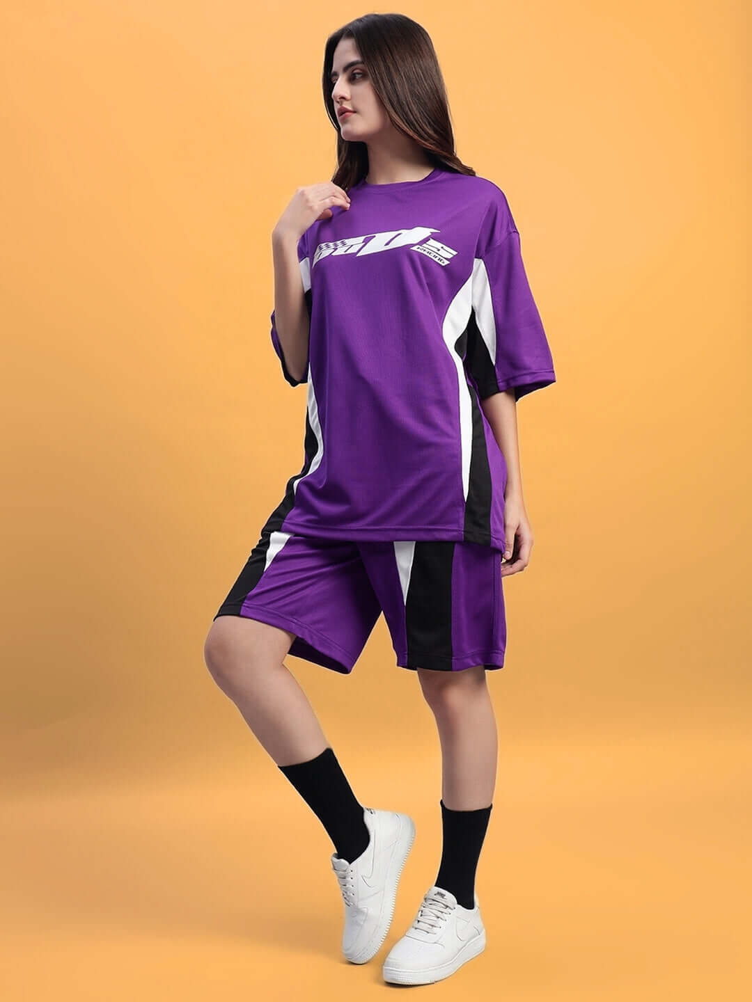 Model wearing Women's FIFA colorblock co-ord set in purple, made from sports polyester fabric, posing against a yellow background.