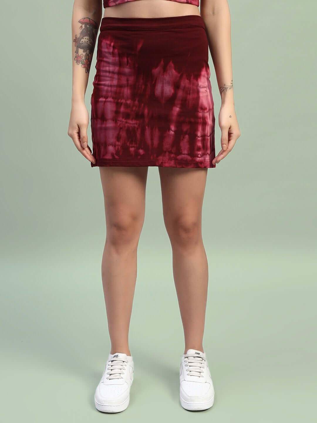 Model wearing maroon tie-dye co-ord set skirt with white sneakers, showcasing Women's Layra Tie-Dye Co-Ord Set in a modern style.