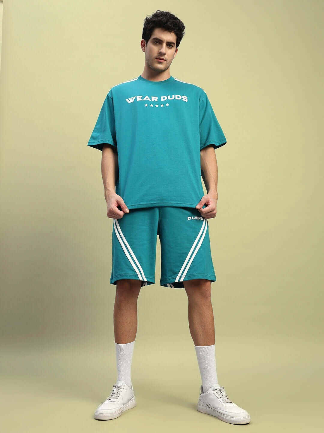 Man wearing STAR JUMPER Regular Fit Shorts in teal by DUDS, featuring a trendy design with white stripes, ideal for casual wear.