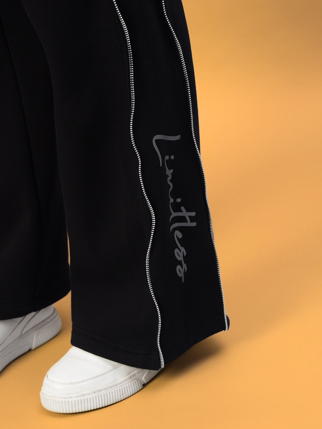 Close-up of black Women's Limitless Fleece Reflector Jogger with white sneakers, highlighting elegant reflective detailing and custom fit option.