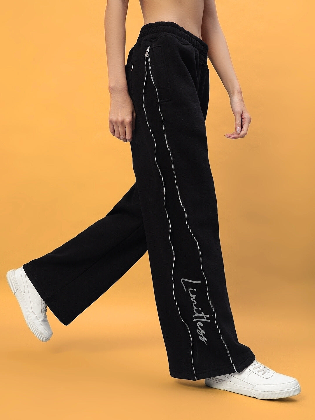 Women's Limitless Fleece Reflector Jogger in black with side zipper and logo detail, paired with white sneakers.