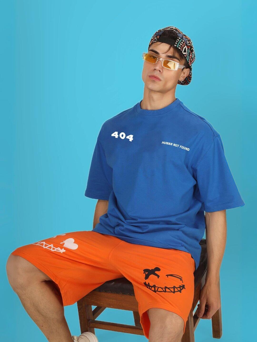 Model wearing 404 ERROR OVER-SIZED T-SHIRT ROYAL BLUE with orange shorts, showcasing a tech-themed style for developers and coders.