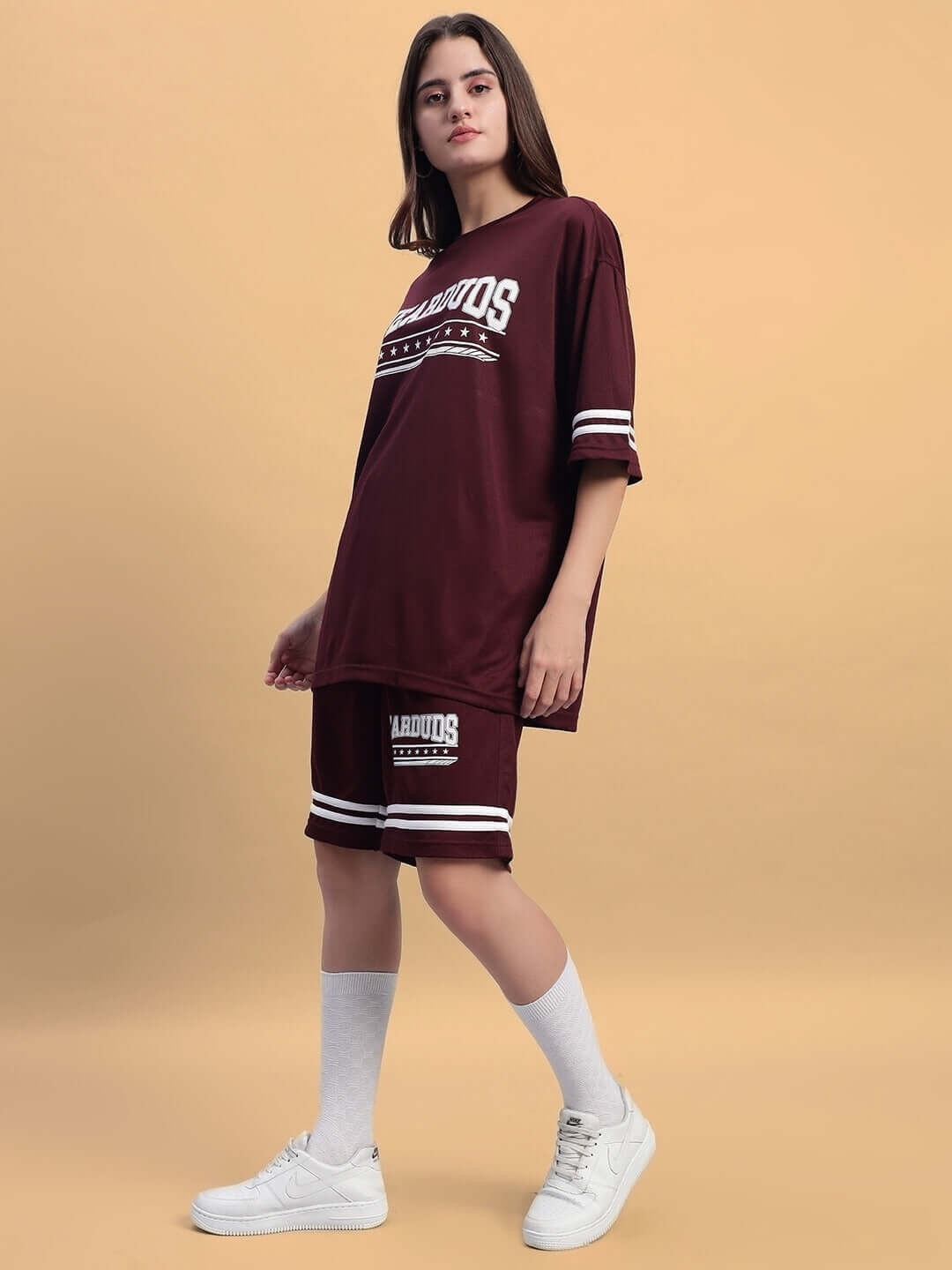 Model wearing wine colorblock co-ord set with sports polyester fabric featuring oversized top and shorts, styled with white socks and sneakers.