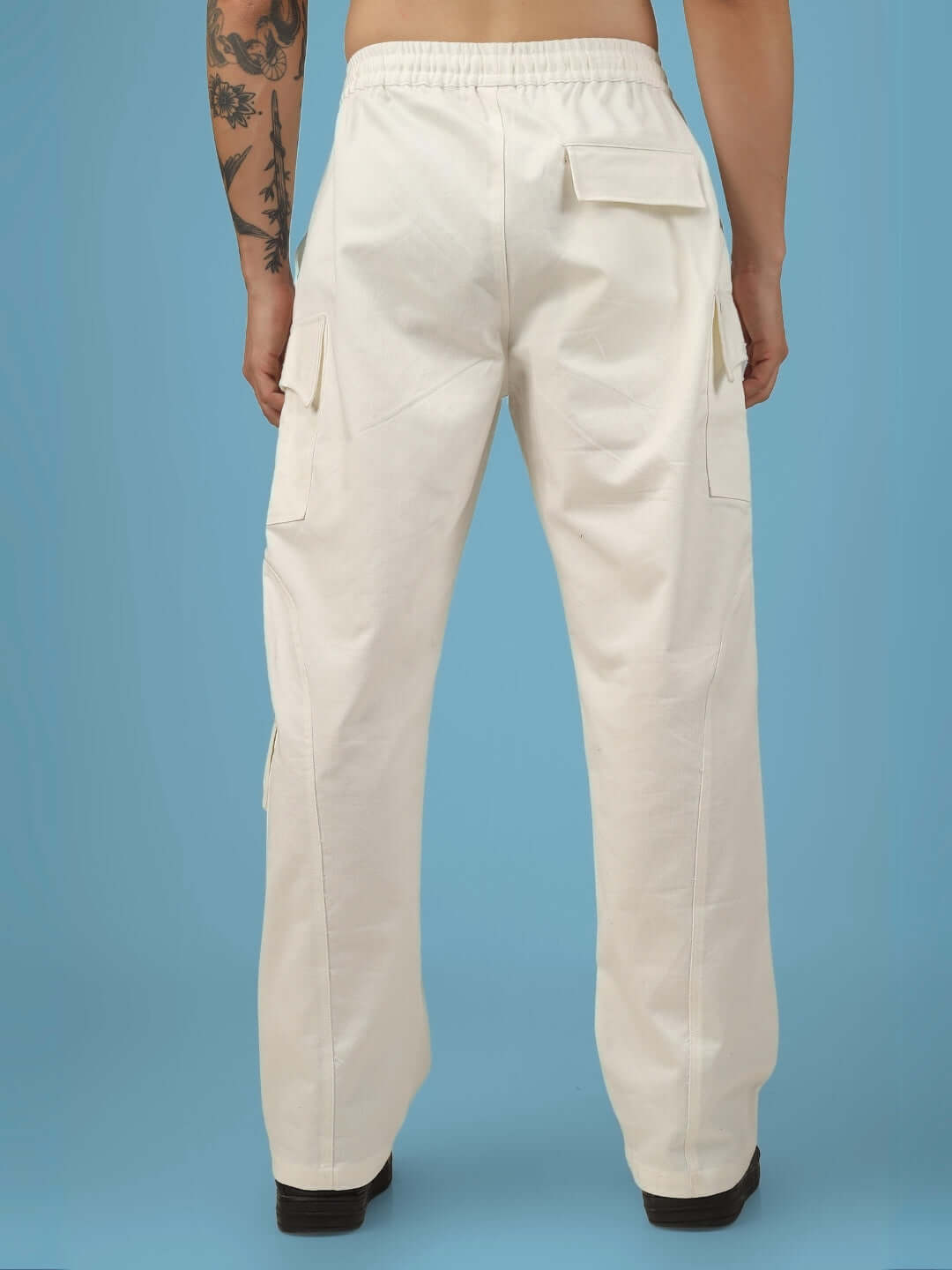 Back view of 6 pocket cotton twill cargo pants in white, showcased by a model against a blue background, highlighting pocket details.