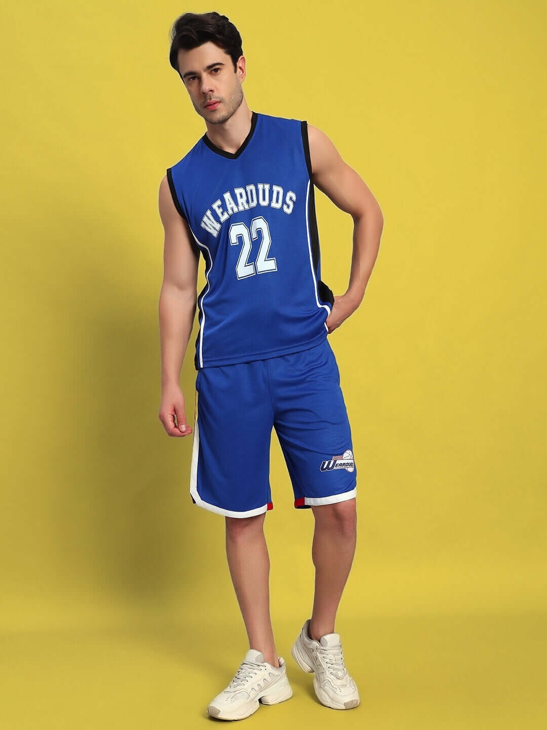 Person modeling a royal blue gym co-ord set with jersey and shorts on a yellow background.