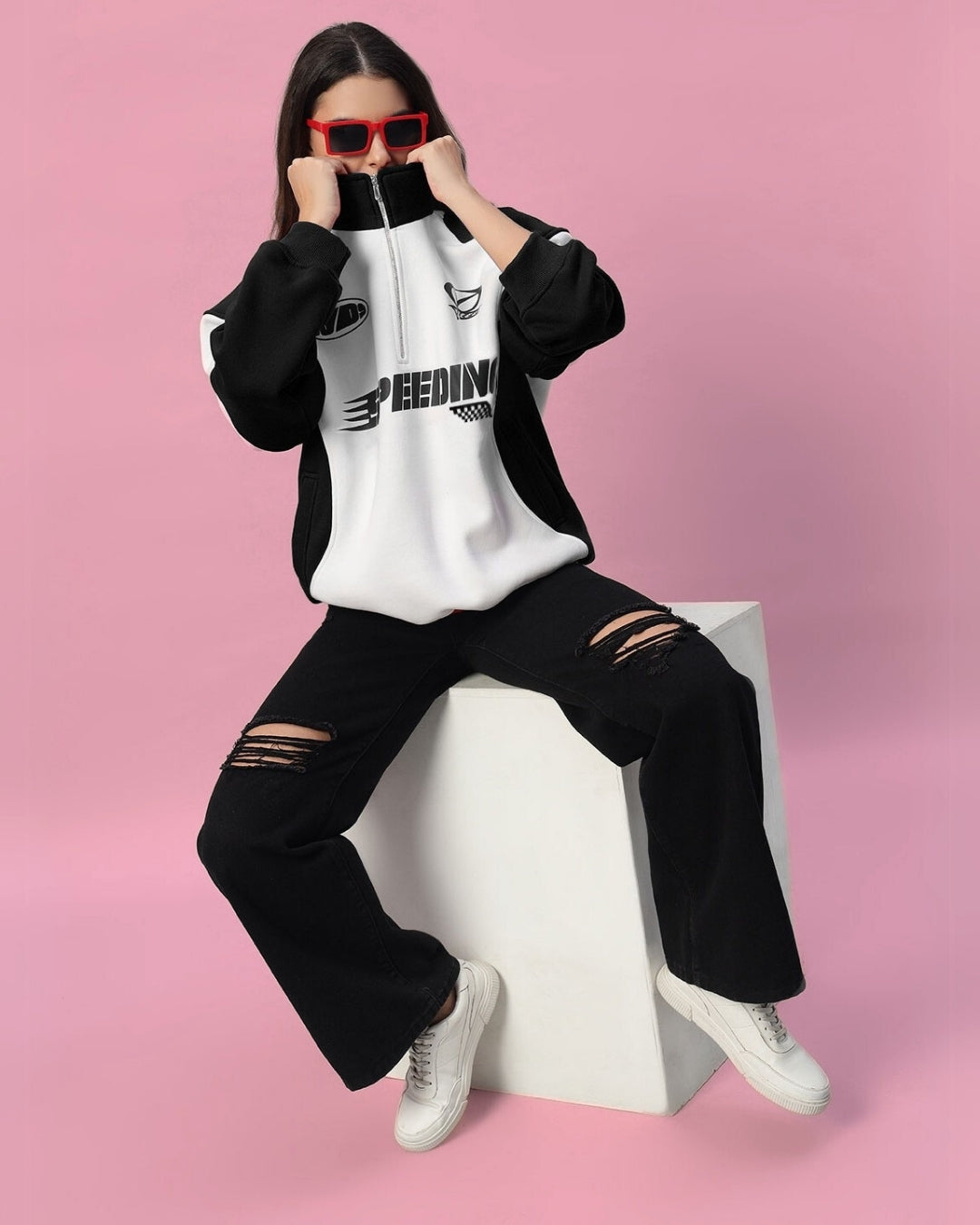 Model wearing Women's Speeding Colorblock Jacket in black with ripped jeans, styled with red sunglasses against a pink background.
